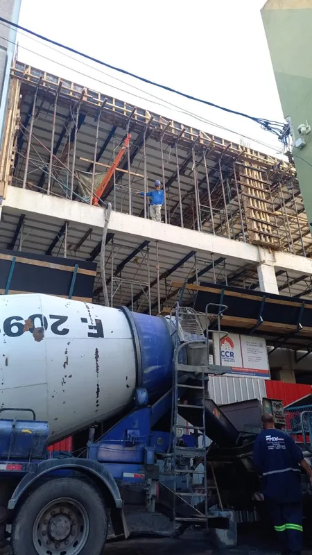 Estrutura de concreto em construção, com formas, escoramento e caminhão-betoneira.
